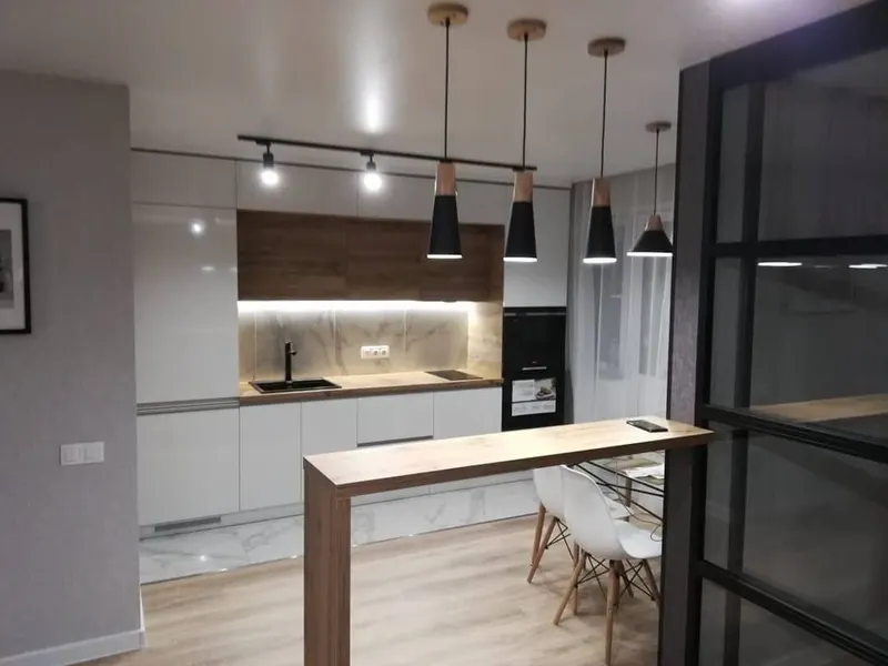 Белая кухня с барной стойкой и подвесными светильниками